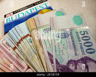 Stapel von Forint, der Währung, die in Ungarn verwendet wird, mit einem Reiseführer für Budapest Stockfoto