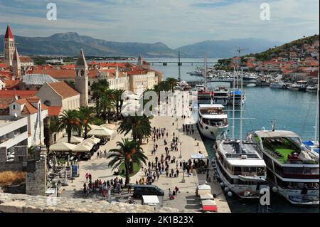 Hoher Blick auf den Hafen von Trogir mit Booten und Touristen in der Ferne. Foto vom Burgturm in Trogir, Kroatien. Stockfoto