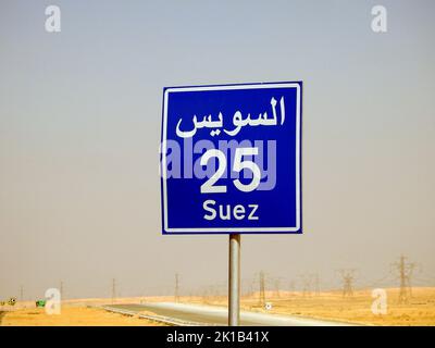 Suez, Ägypten, August 12 2022: Ein Straßenschild in Suez Kairo Autobahn gibt die verbleibende Entfernung zur Stadt Suez 25 KM fünfundzwanzig Kilometer in geschrieben Stockfoto