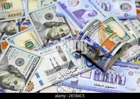 American Money roll with a Band on a pile of American Dollar Geldscheine American Cash Money Banknoten mit Saudi-Arabien riyals Geldscheine und New Emir Stockfoto