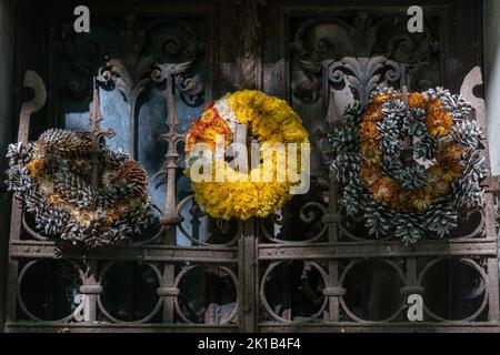 Alte Kränze aus trockenen Blumen und Zapfen gemacht und auf Grab rostigen Metall-Tor auf dem Friedhof gelegt. Stockfoto