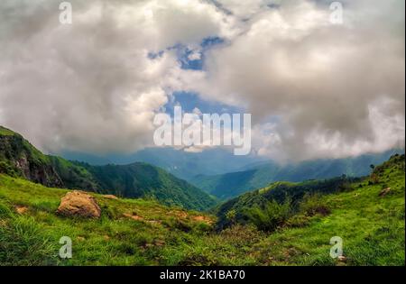 Dicke Monsunwolken schweben über üppig grüne Berge mit tiefer Schlucht am Stadtrand von Mawsynram, East Khasi Hills, Meghalaya, Indien. Stockfoto