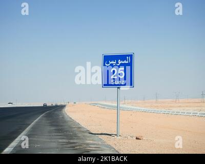 Suez, Ägypten, August 12 2022: Ein Straßenschild in Suez Kairo Autobahn gibt die verbleibende Entfernung zur Stadt Suez 25 KM fünfundzwanzig Kilometer in geschrieben Stockfoto