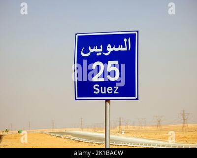 Suez, Ägypten, August 12 2022: Ein Straßenschild in Suez Kairo Autobahn gibt die verbleibende Entfernung zur Stadt Suez 25 KM fünfundzwanzig Kilometer in geschrieben Stockfoto