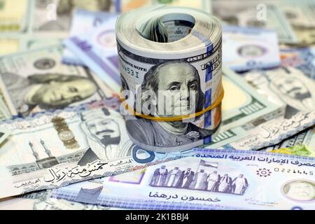 American Money roll with a Band on a pile of American Dollar Geldscheine American Cash Money Banknoten mit Saudi-Arabien riyals Geldscheine und New Emir Stockfoto