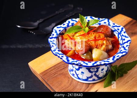 Thai Food Konzept Roasted Chicken Red, auf Holzbrett auf schwarzem Hintergrund mit Kopierfläche Stockfoto