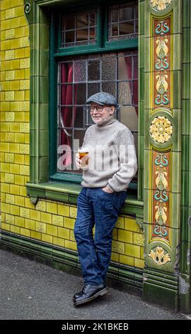 Mann steht vor einem Pub und genießt einen Drink im Peveril of the Peak , das sich in der Great Bridgewater Street in Manchester, England, befindet Stockfoto