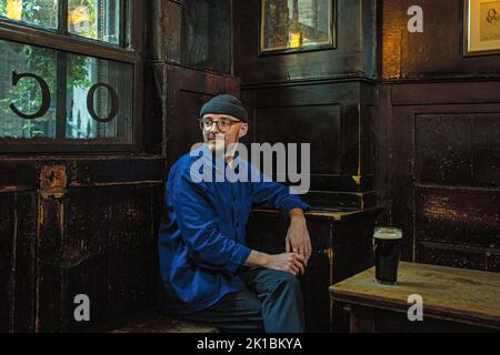 Junger Mann trinkt Bier in einem traditionellen Pub, dem Ye Olde-Käse, The City of London, Großbritannien. Stockfoto