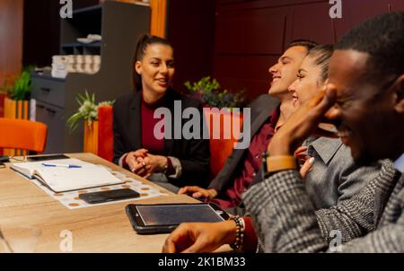 Eine Gruppe von multirassischen Geschäftsleuten redet und lächelt, während sie sitzen Stockfoto