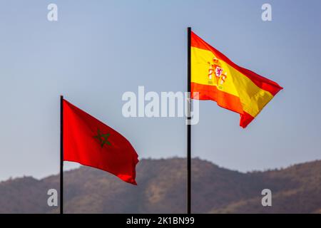 Die Nationalflagge von marokko und spanien winkt in einem blauen Himmel Stockfoto