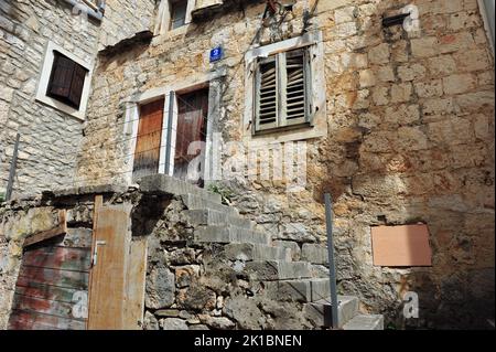 Mittelalterliches Gebäude mit Treppe davor. Kaputte Fensterläden und verfallende Wände. Stockfoto