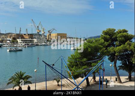 Hafen in Trogir, Kroatien. Segelboote und Hebezeuge im Hintergrund. Spielplatz im Vordergrund. Stockfoto