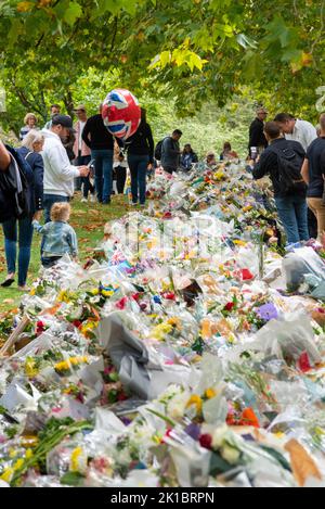 Menschen lesen Botschaften mit Blumen im Green Park nach dem Tod von Königin Elizabeth II. Blumensträuße mit Kunststoffverpackung im Park angelegt Stockfoto