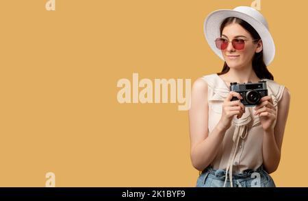 Halten Sie Momente fest. Sommerurlaub. Denken Sie an die Reise. Glückliche Frau Sonnenbrille Strohhut hält Fotokamera suchen Kopie Raum isoliert auf beige. Werbung Stockfoto