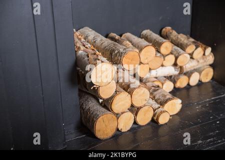 Vorrat an Brennholz zum Heizen des Hauses, Brennstoff in Kaminen und Öfen. Großer Holzstapel.Stapel von großen Holzstämmen aus trockenem Brennholz, gestapelt drinnen, ist das Haus Stockfoto