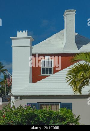 Bermuda-Architektur Tiefe orange-rote und rosa Häuser mit weißen Kaminen und Dächern vor hellem blauen Himmel aus nächster Nähe Stockfoto