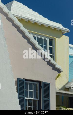 Bermuda-Architektur Bunte rosa-gelbe und türkise Häuser mit weißen Dächern und tiefblauem Himmel aus nächster Nähe Stockfoto