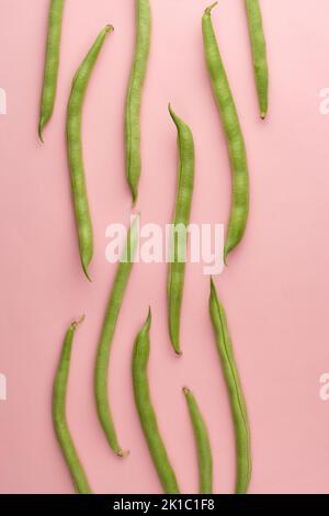 Grüne Bohnen auf hellrosa Hintergrund, auch bekannt als französische Bohnen, Schnur Bohnen oder Druckknöpfe, Gemüsemuster Stockfoto