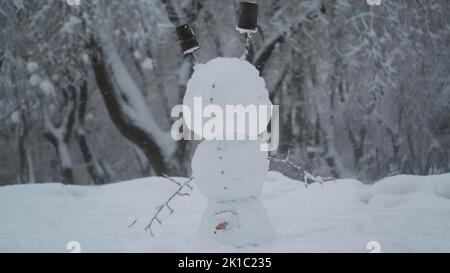 Fröhlicher lustiger Schneemann akrobatin auf dem Kopf, vor dem Hintergrund eines starken Schneefalls. Schneemann steht auf seinem Kopf. Odessa, Ukraine Stockfoto