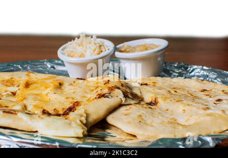 Nahaufnahme von köstlichen salvadorianischen Pupusas mit Käse auf dem Tisch serviert. Traditionelle Pupusas mit Salat auf dem Tisch. Zwei nicaraguanische Pupusas Stockfoto