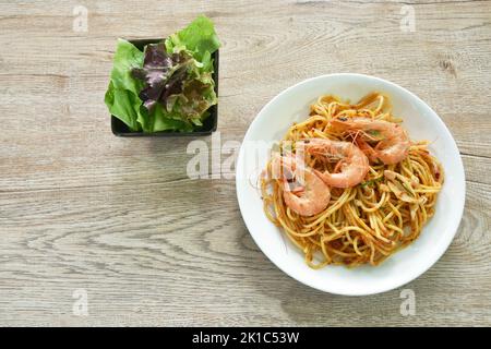 Würzig gebratene Spaghetti-Garnelen mit Chili und Basilikum in tom-Yum-Sauce auf dem Teller essen paar frischen Gemüsesalat Stockfoto