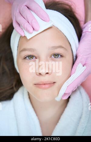Weibliche Hände wischen Mädchen Gesicht mit Servietten im Schönheitssalon Stockfoto