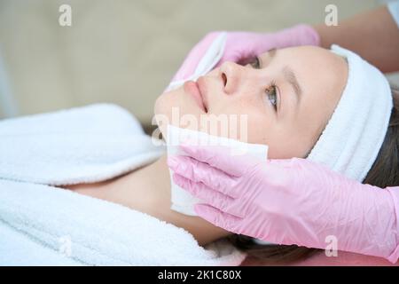 Weibliche Hände wischen Mädchen Gesicht mit Servietten nach Kosmetologie Verfahren Stockfoto