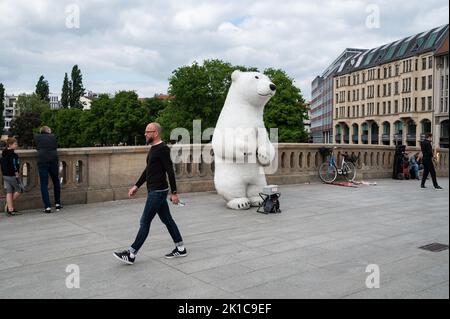 14.05.2022, Berlin, Deutschland, Europa - der Mensch überquert die Friedrichsbrücke im Stadtteil Mitte, während ein Straßenkünstler in einem Eisbären-Kostüm ist. Stockfoto