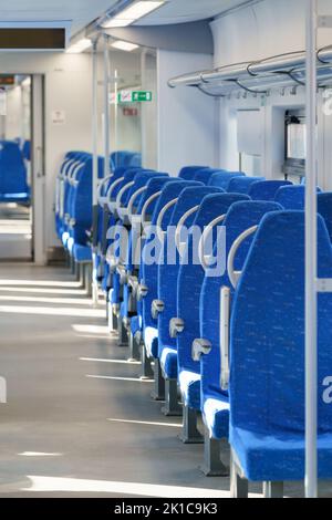 Innenraum des modernen Hochgeschwindigkeits-Expresszuges für Passagiere, Reihe leerer, weicher Sitze aus blauem Stoff. Stockfoto