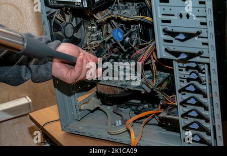 Dnepropetrovsk, Ukraine - 11.27.2021: Reinigung der Systemeinheit eines Desktop-Computers mit einem Staubsauger von Staub. Stockfoto