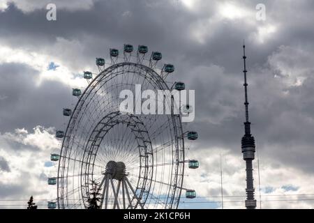 Moskau, Russland. 17.. September 2022. Blick auf die Sonne von Moskau Riesenrad und den Ostankino Fernsehturm auf dem VDNKh Ausstellungszentrum und Park in Moskau, Russland Stockfoto