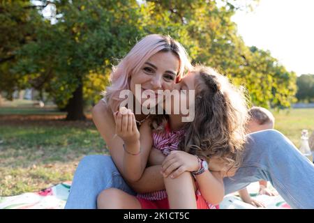 Tochter gibt ihrer Mutter einen Kuss während eines Picknicks, Liebe zwischen Mutter und Tochter Stockfoto