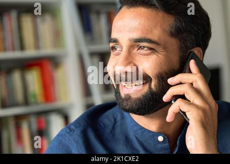 Lächelnder indischer Geschäftsmann, der am Telefon telefoniert und aus der Nähe telefoniert. Stockfoto