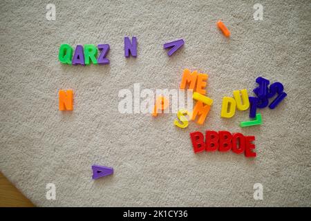Magnet-Alphabet-Spielzeug zufällig auf einen weißen Teppich gelegt. Stockfoto