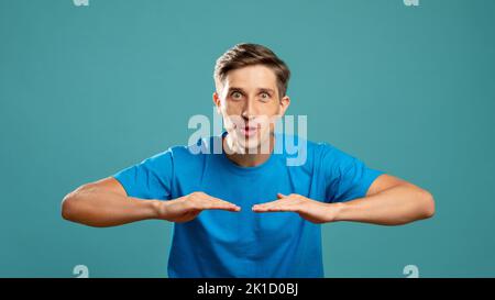 Aufgeregtes Männerportrait. Wow-Gefühl. Fähigkeiten der Schauspieler. Hohes Niveau. Unsichtbare Informationen. Junger, überraschender Mann, der die Kamera anschaut und die Hände vor c hält Stockfoto