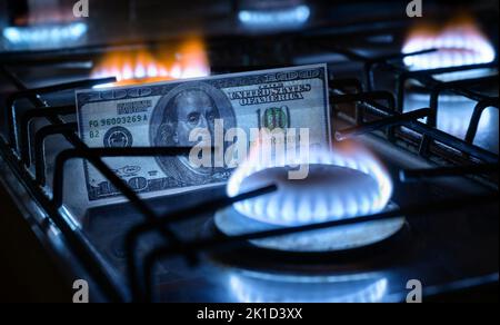 Gasbrenner und US-Dollar-Rechnung, US-Geld auf heimigem Gasherd, blaue Propan-Flamme und Währung. Konzept der Weltwirtschaft, Energiekrise, Öl, russische na Stockfoto