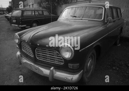 Eine Graustufenaufnahme eines alten Volvo-Autos, das auf einem verlassenen Parkplatz geparkt wurde Stockfoto