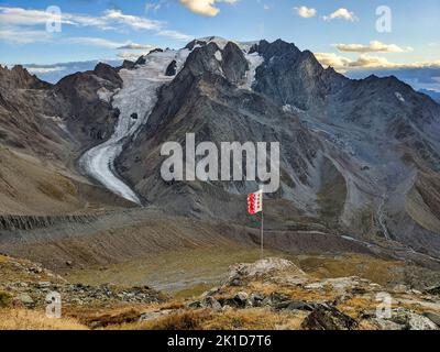 Blick auf den Mont Velan von der cabane de Valsorey mit Walliser Flagge im Wind. Bergtour in den Schweizer Bergen Stockfoto