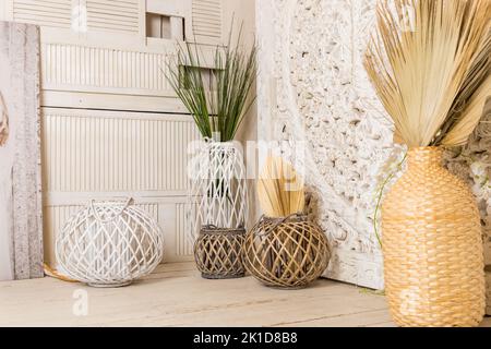 Stilvolles Konzept der Wohnzimmereinrichtung mit getrocknetem Blatt in Vase, Rattan-Körben, Pflanze, Holzwand und persönlichen Accessoires in Home decor.hygge Stockfoto