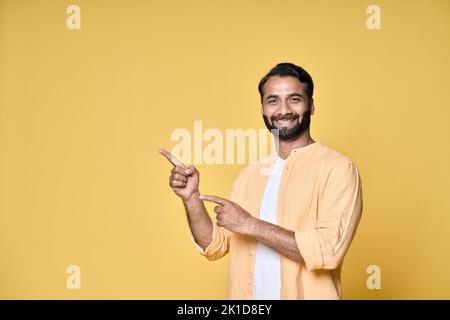 Glücklich indischen Mann zeigt Finger Werbung isoliert auf gelbem Hintergrund. Stockfoto