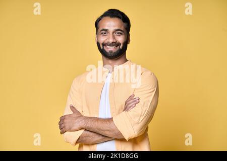 Lächelnder, selbstbewusster bärtiger indischer Mann, der isoliert auf gelbem Hintergrund steht. Stockfoto