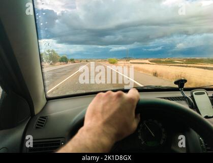 Fahrt unter dem stürmischen Himmel bei Sonnenuntergang. Blick von innen Stockfoto