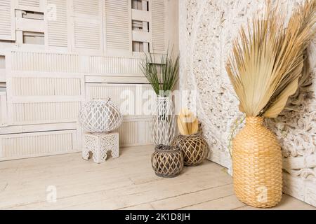 Stilvolles Konzept der Wohnzimmereinrichtung mit getrocknetem Blatt in Vase, Rattan-Körben, Pflanze, Holzwand und persönlichen Accessoires in Home decor.hygge Stockfoto