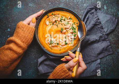 Weibliche Hände mit Schale Kürbissuppe Stockfoto