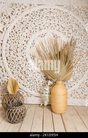 Stilvolles Konzept der Wohnzimmereinrichtung mit getrocknetem Blatt in Vase, Rattan-Körben, Pflanze, Holzwand und persönlichen Accessoires in Home decor.hygge Stockfoto