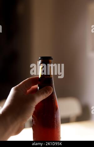 Hand hält eine Flasche Bier in einem Haus Stockfoto