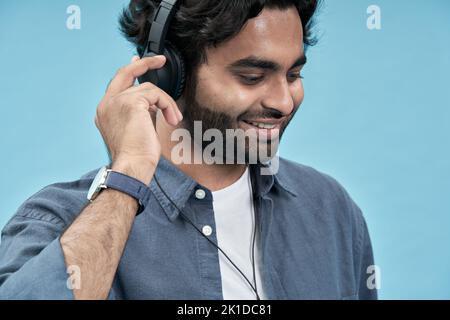 Lächelnder arabischer Student, der Kopfhörer trägt und Musik hört. Nahaufnahme Stockfoto