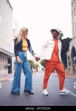 Glückliches interrassisches Paar mit Modebekleidung in einer städtischen Stadtstraße mit einem Lächeln und Liebe. Trendy, stylish oder Punk Mann und Frau zu Fuß in einer Stadt Stockfoto