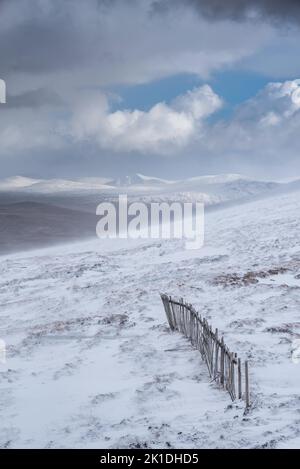 Wunderschöne Winterlandschaft von der Bergspitze in den schottischen Highlands hinunter in Richtung Rannoch Moor während Schneesturm und Spindrift von der Bergspitze hinein Stockfoto