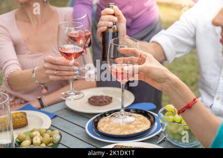 Nahaufnahme eines Toasts mit Rotweingläsern. Schöne Farben Hände und Licht. Stockfoto